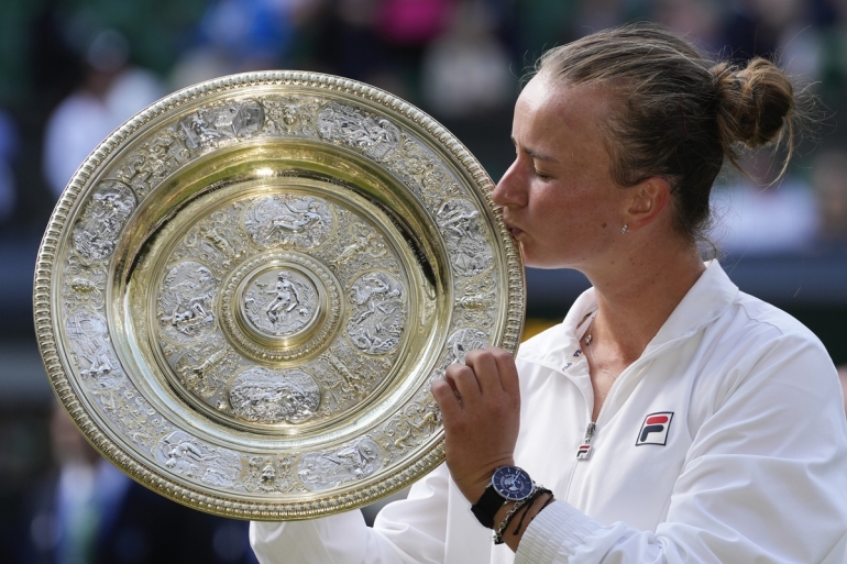 Petenis Ceko Barbora Krejcikova mencium trofi juara Wimbledon setelah mengalahkan petenis Italia Jasmine Paolini pada partai final di London, Sabtu (13/7/2024). AP PHOTO/KIRSTY WIGGLESWORTH via Kompas.id